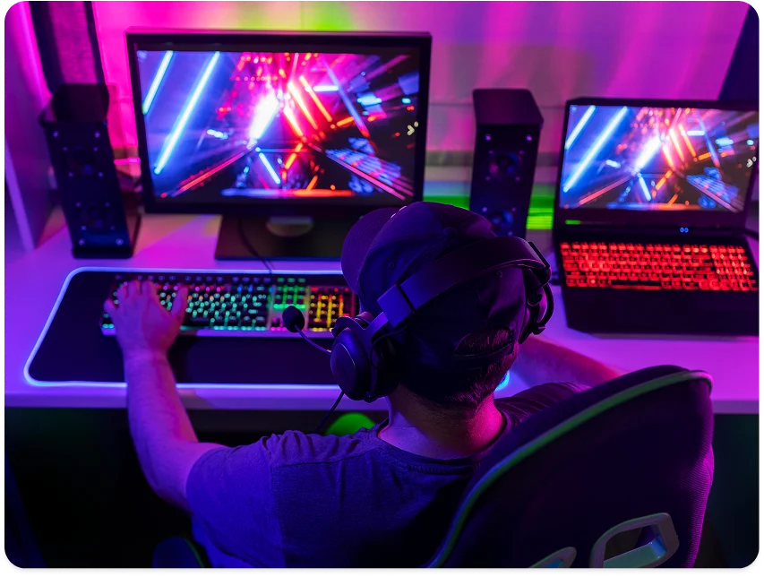 Gamer achter een professionele opstelling met meerdere schermen en kleurrijke RGB-verlichting